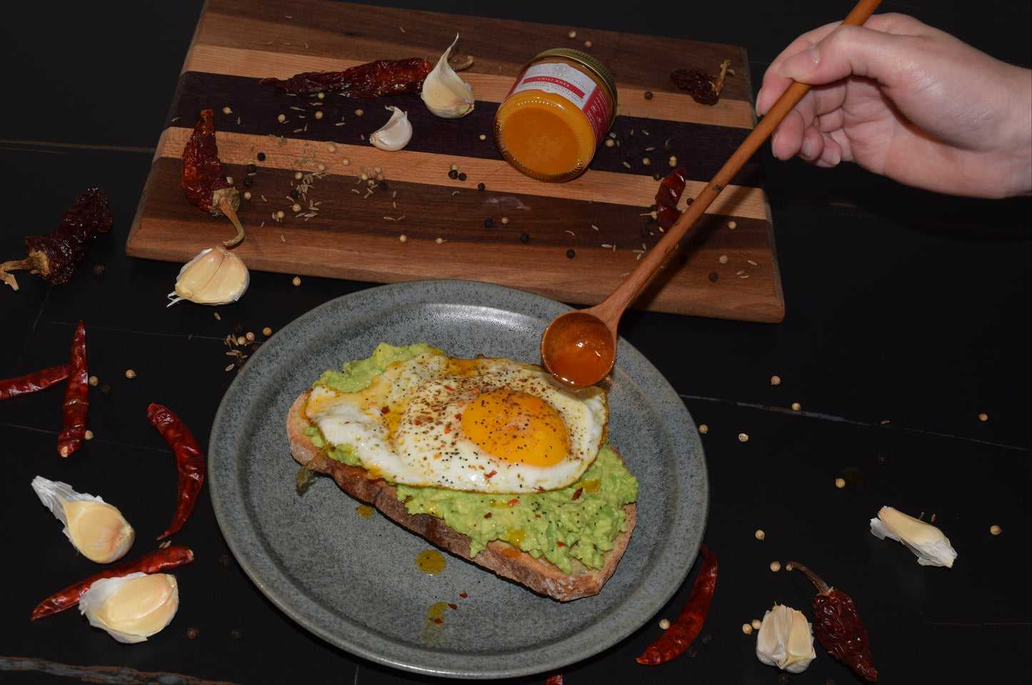 A plate of avocado toast topped with a fried egg and drizzled with Ahara Rasa Chili Ghee