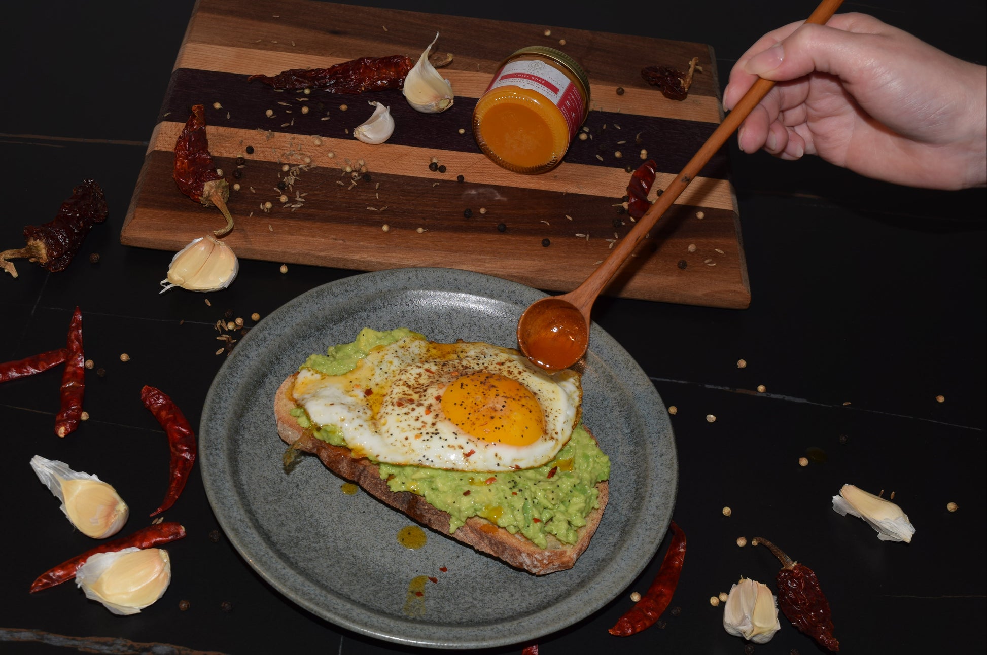 A plate of avocado toast topped with a fried egg and drizzled with Ahara Rasa Chili Ghee